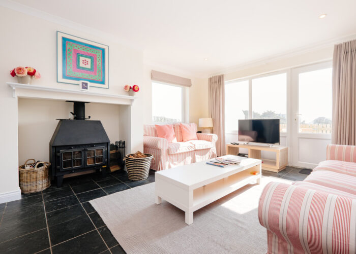 Highcliffe Holidays' stylish Nantucket cottage sitting room with a log-burning stove.