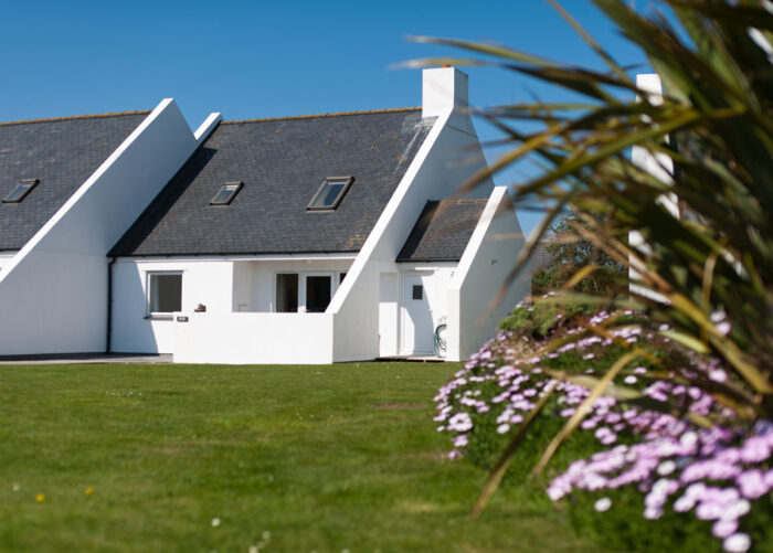 The outside of the cottage Ross on Highcliffe Holidays' estate shows beautiful flowers and a well-looked-after lawn.