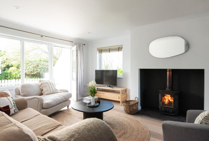 Bright, comfy sitting room with log burner and doors leading to patio.